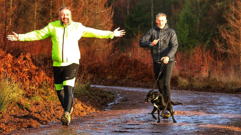 Two men running with a dog