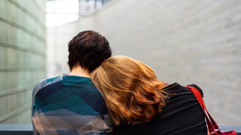 Image of two people, one with their head on the other's shoulder