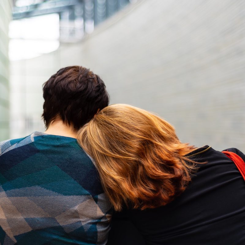 Image of two people, one with their head on the other's shoulder