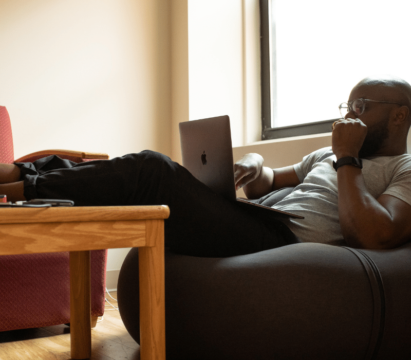 Man on beanbag on a laptop.