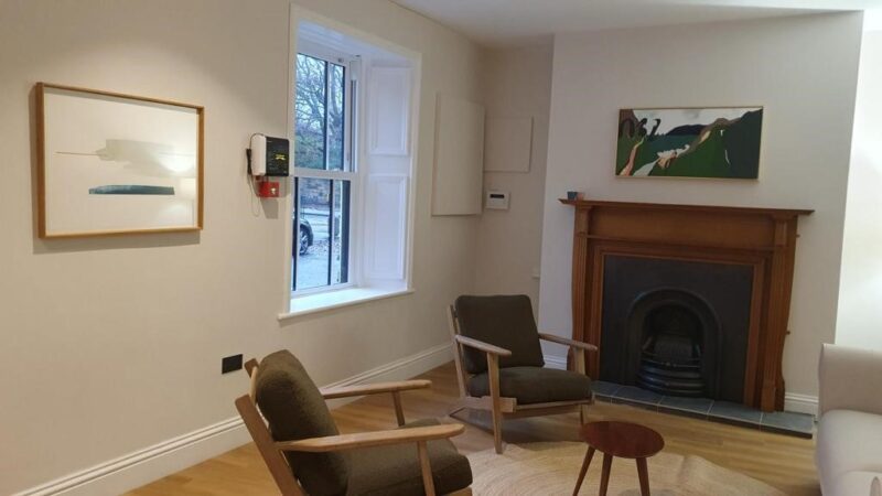 Image of room with fireplace, chairs and artwork