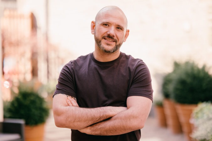 Man with arms folded smiling at camera