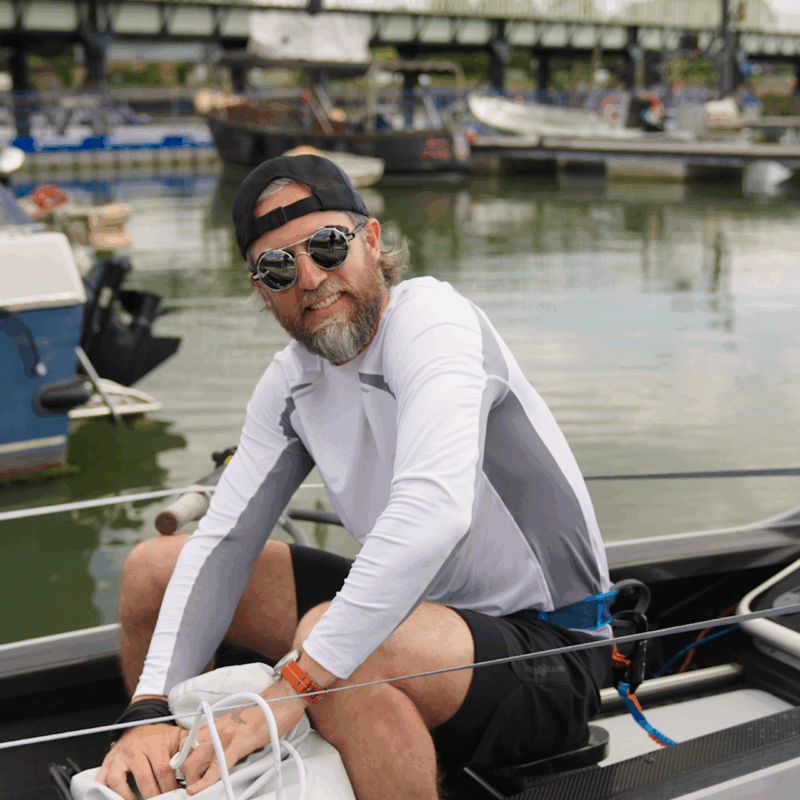 Man in sunglasses smiling whilst looking a boat